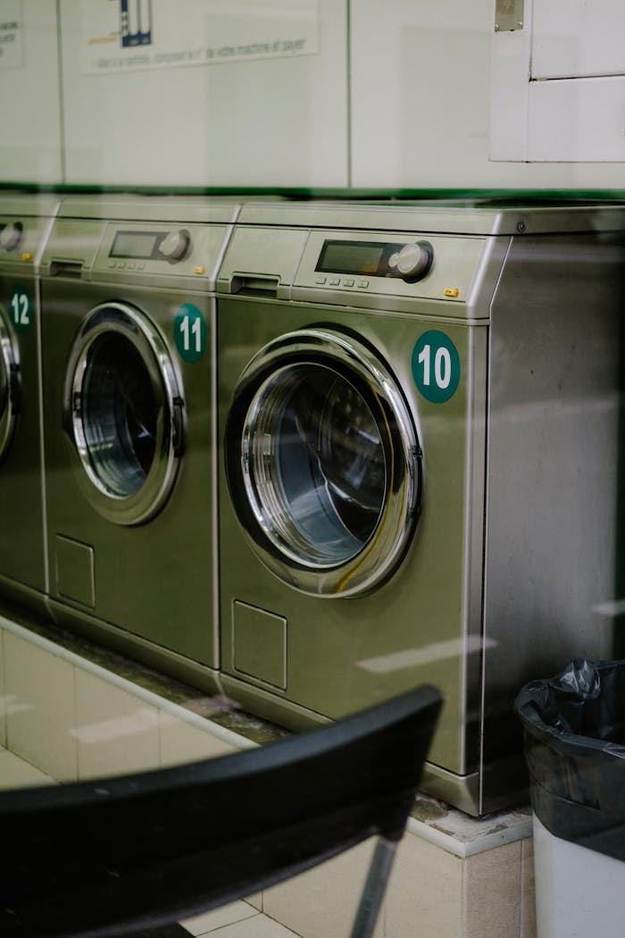 A clean, modern laundromat with stainless steel washing machines lined up.