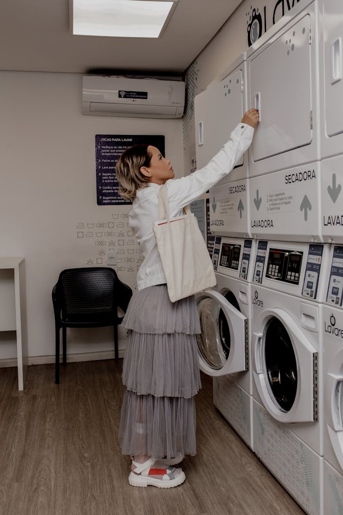A woman operates a washing machine in a modern laundromat with stylish interior design.